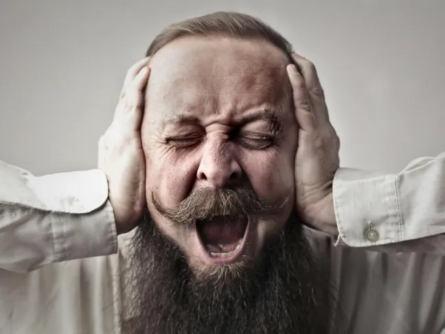 Mann hält sich die Ohren zu